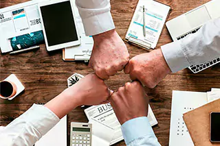 Fists coming together over an office desk.